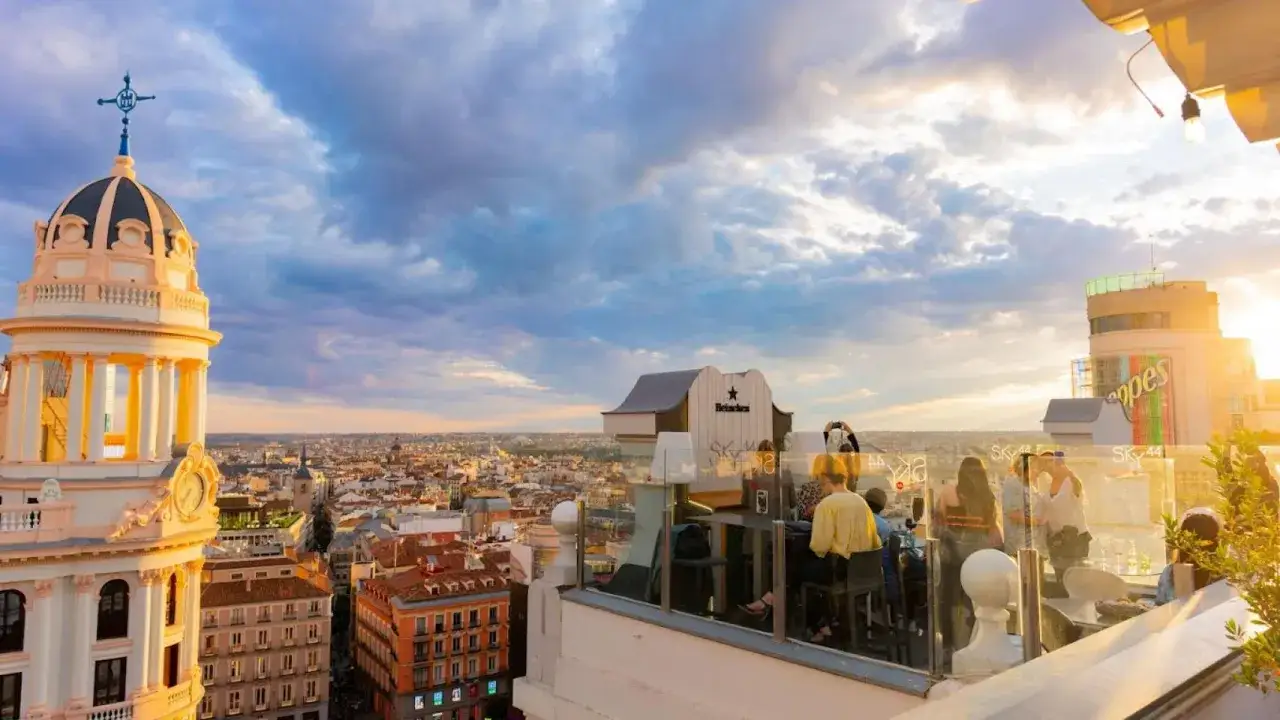 Disfruta de unas terrazas azoteas Madrid baratas con vistas espectaculares al atardecer. Gente relajada en un bar en la azotea.