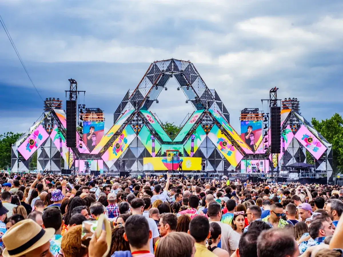 Multitud en un festival con un escenario gigante y colorido. ¡Me encanta el ambiente de tuenti's!