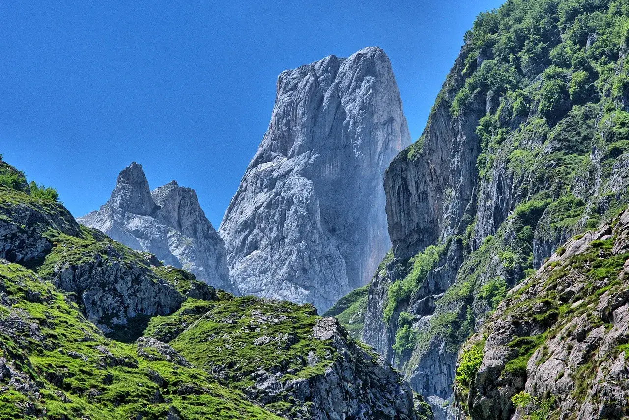 Majestuosas montañas de la provincia más montañosa de España, con picos rocosos y laderas verdes bajo un cielo azul.