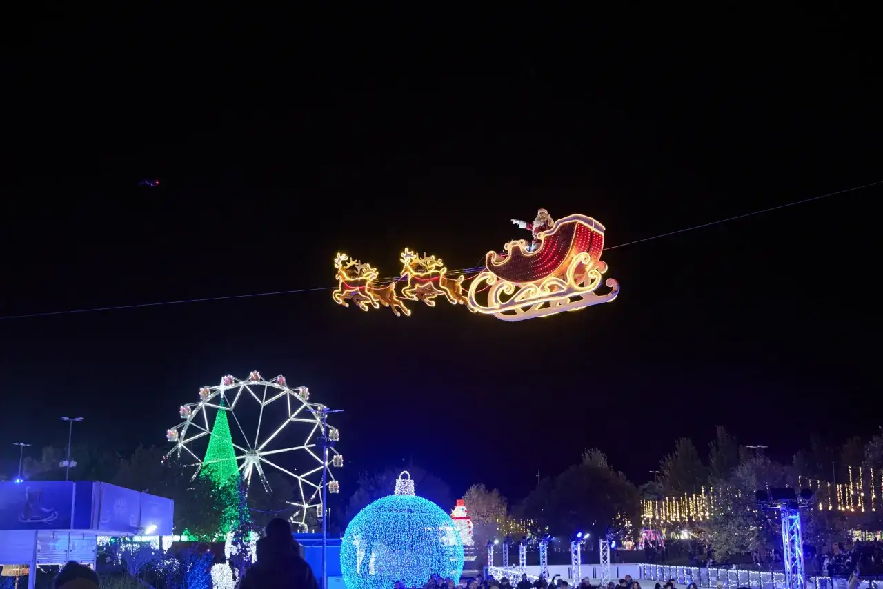 Trineo de Pap&aacute; Noel ilumina la noche en la ciudad de la Navidad Madrid. Rueda de la fortuna y &aacute;rbol gigante de luces brillan.