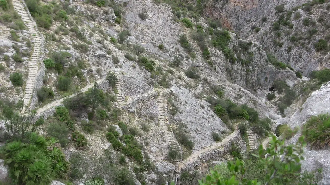 Senderos empedrados serpentean por el árido paisaje del barranc de l'infern, desafiando la gravedad.