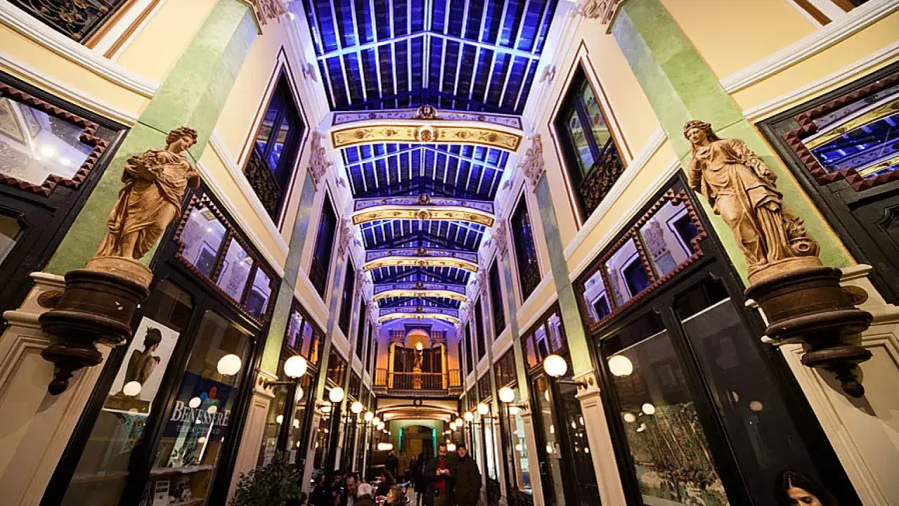 Pasaje cubierto con estatuas y luces azules, un lugar bonito que ver en Valladolid.