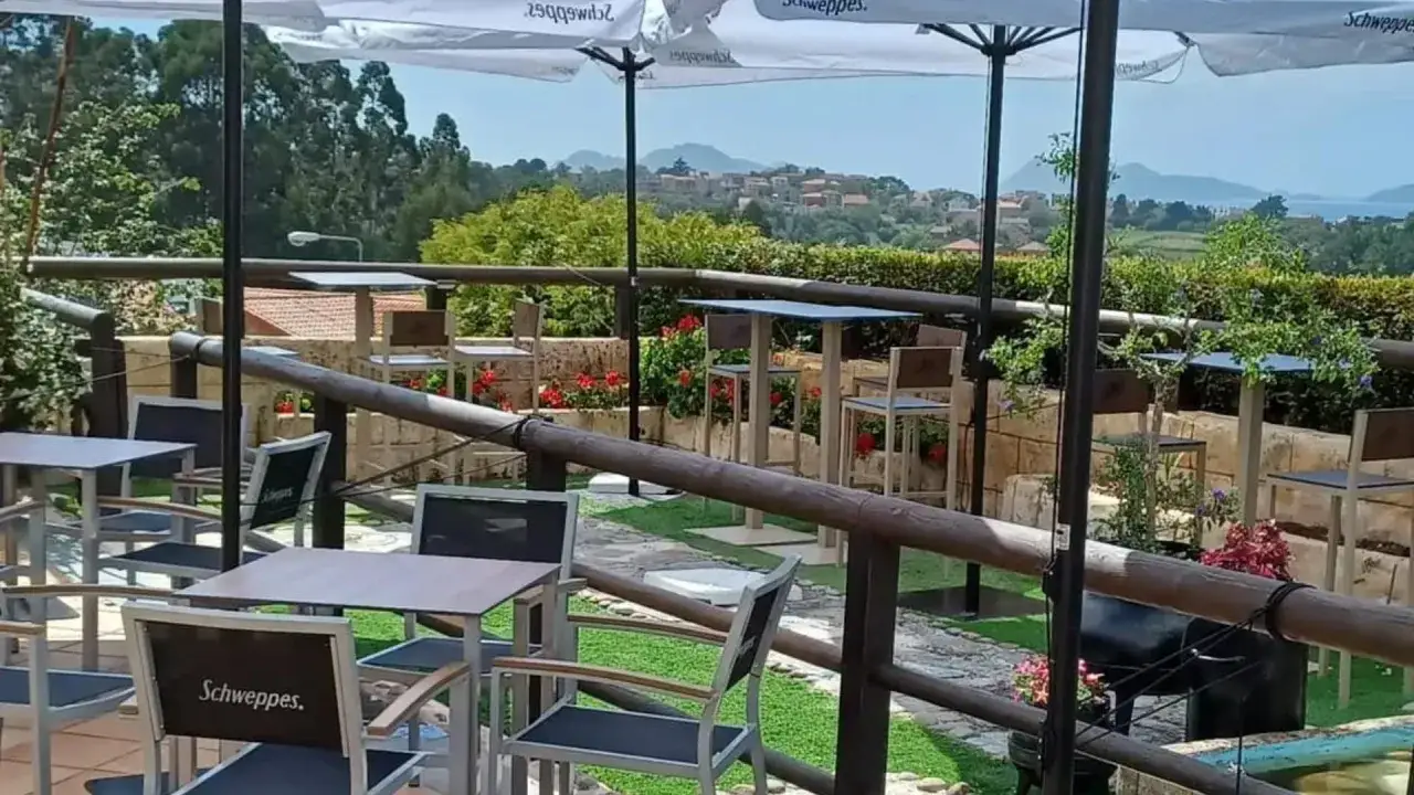 Terraza con mesas y sillas, ideal para disfrutar de restaurantes con encanto en Vigo y alrededores. Vista panor&aacute;mica.