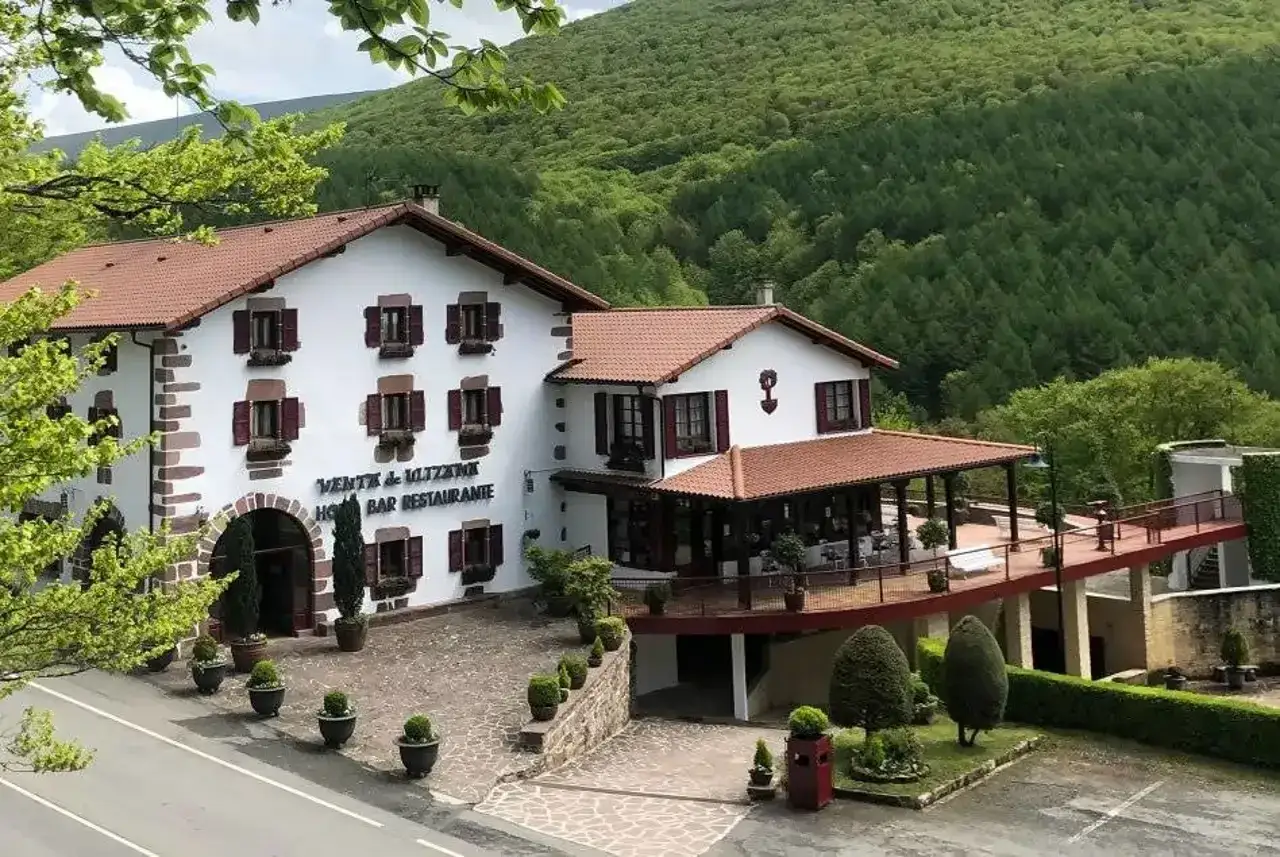 Venta de Liztzen, uno de los restaurantes en pueblos cerca de Pamplona, con su fachada blanca y tejado rojo, rodeado de verde.