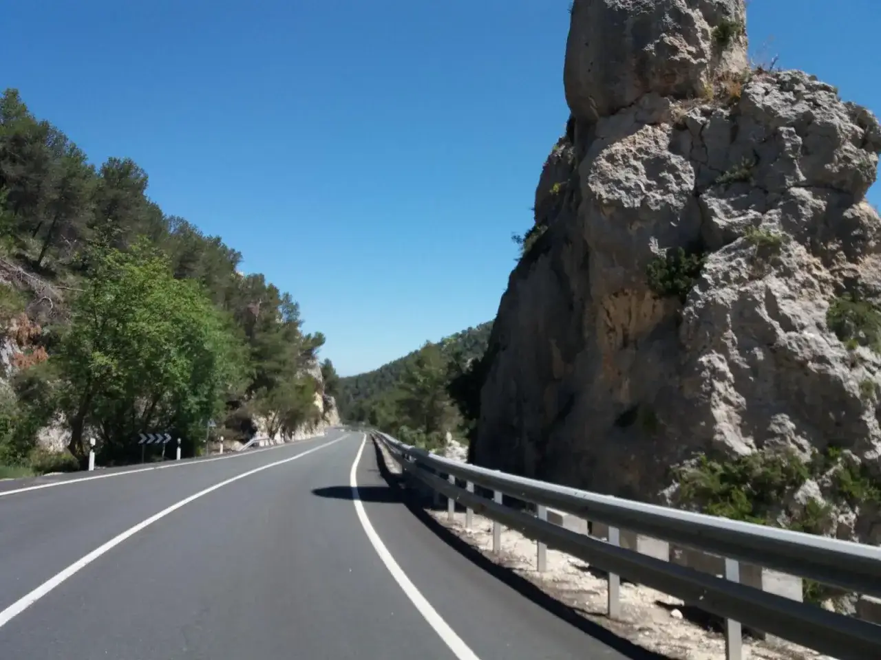 Carretera esc&eacute;nica con rocas imponentes y vegetaci&oacute;n, ideal para tu viaje a Benilloba.