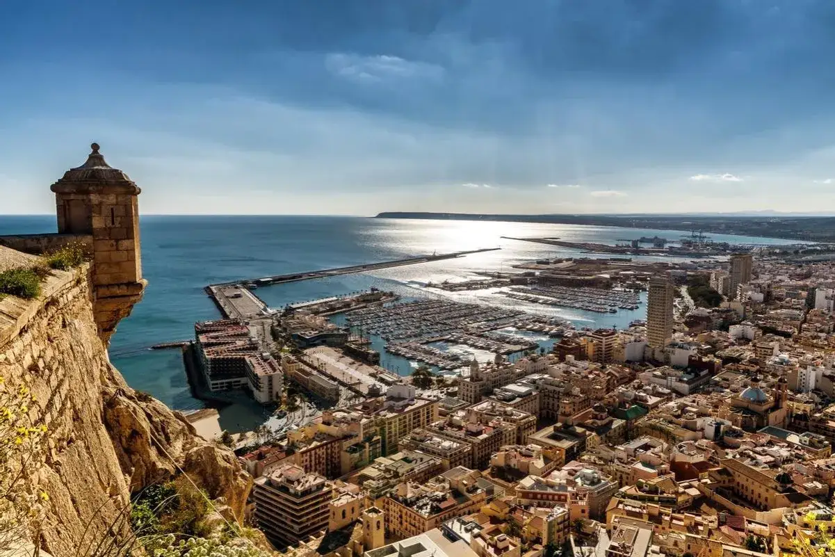Vista panorámica de Alicante desde el castillo. El puerto deportivo lleno de barcos y la ciudad se extienden hasta el mar. ¡Ideal para saber qué ver en Alicante en un día!