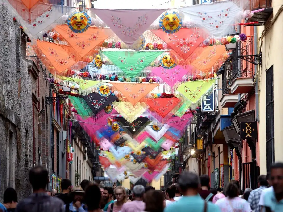Calle engalanada con pañuelos de colores y soles sonrientes para las fiestas San Cayetano Madrid.