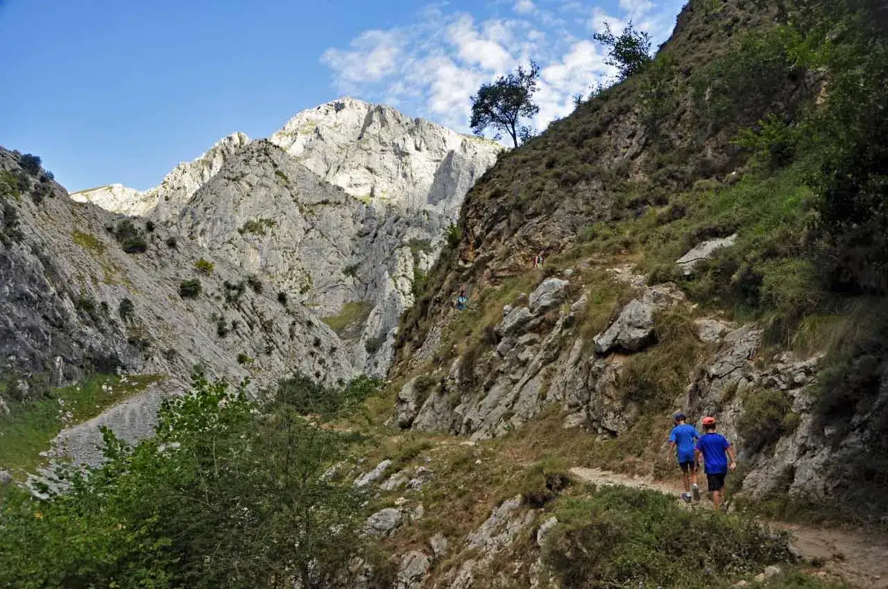 Dos ni&ntilde;os caminan por un sendero rocoso hacia las monta&ntilde;as. As&iacute; es como llegar a Bulnes.