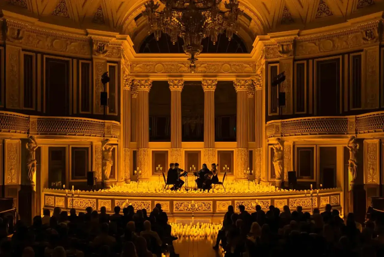 Un concierto de m&uacute;sica cl&aacute;sica con un ambiente de candlelight el se&ntilde;or de los anillos. Un tr&iacute;o de cuerdas toca en un escenario iluminado por miles de velas.
