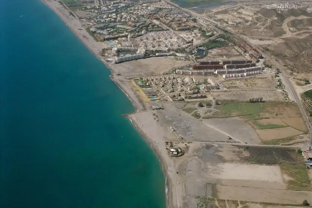 Vista aérea de la playa Quitapellejos, con urbanizaciones y el mar turquesa. Opiniones sobre este lugar son variadas.