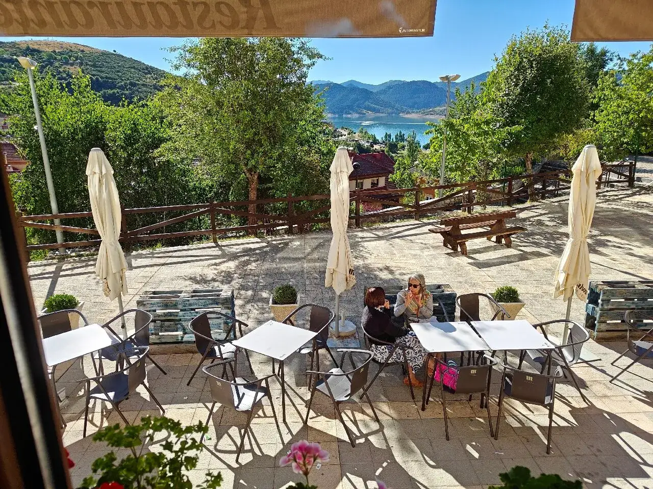 Terraza de restaurante con vistas al embalse. Ideal para saber donde comer en Riaño. Mesas, sillas y sombrillas preparadas.