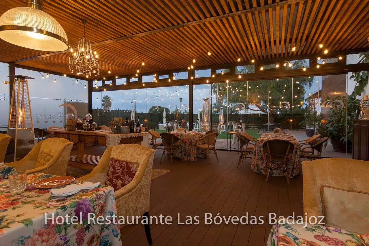 Ambiente acogedor en uno de los mejores restaurantes de Badajoz, con mesas florales y luces c&aacute;lidas.