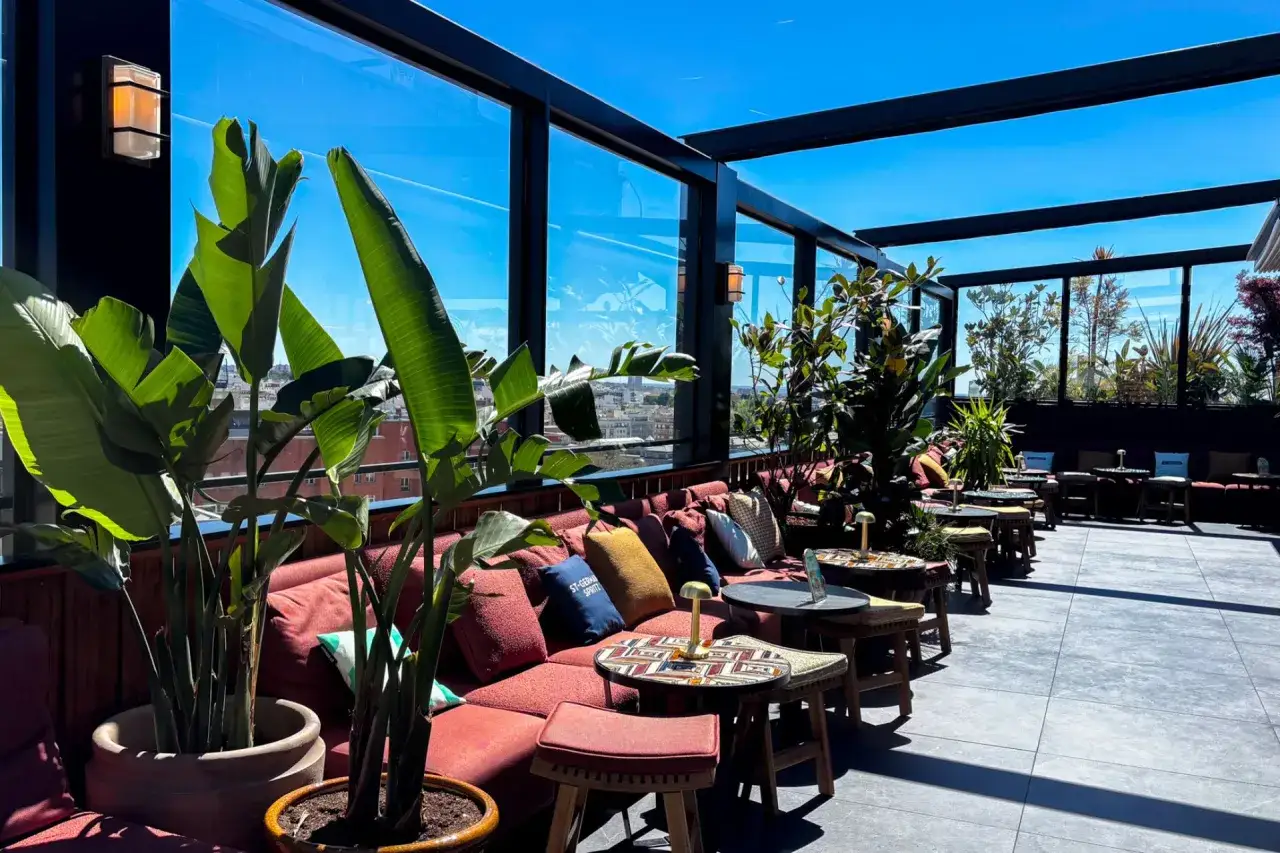 Sofá rojo y plantas en una terraza con vistas a la ciudad. Un lugar perfecto para disfrutar de un día soleado en esta casa suecia rooftop.