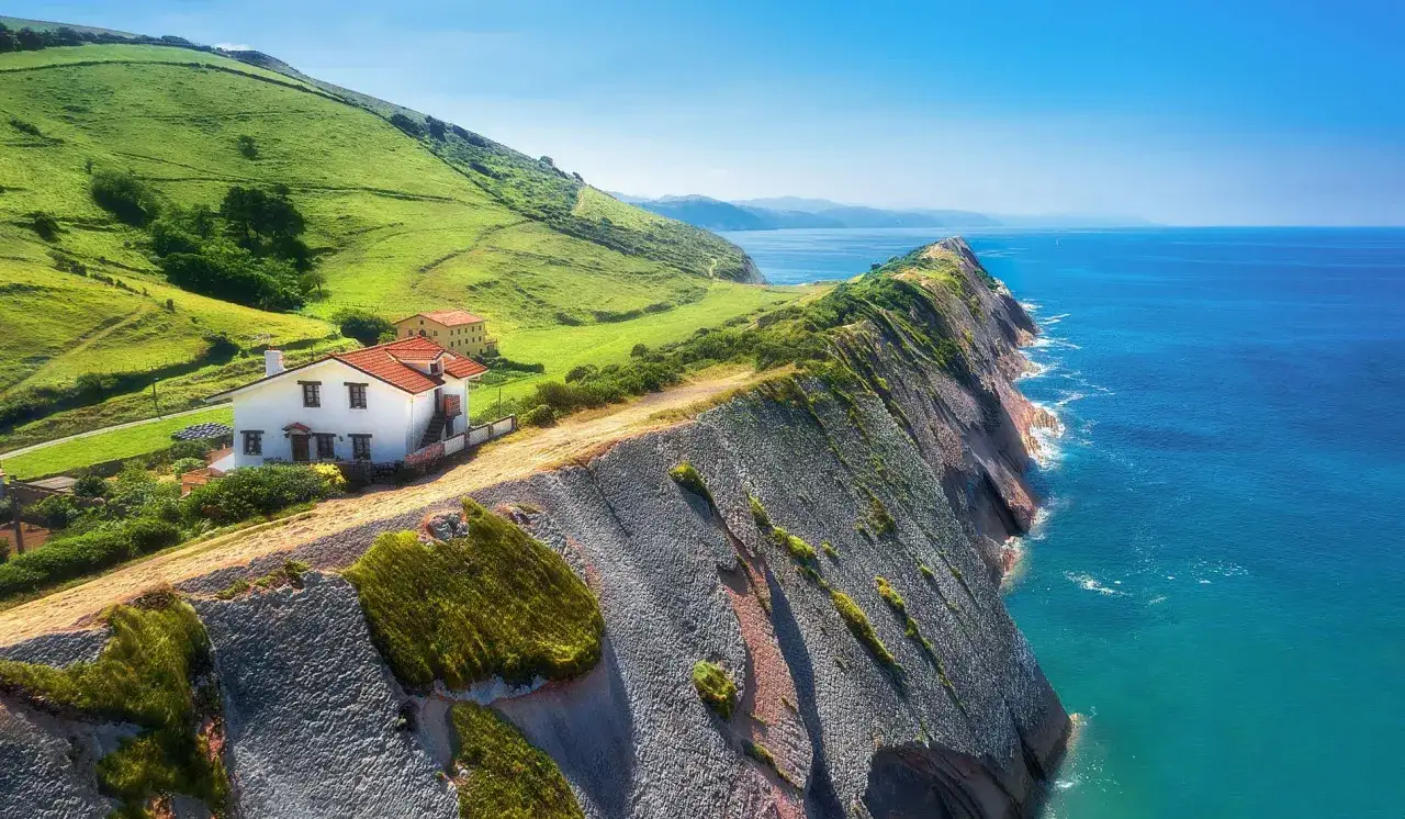 Casas blancas con tejados rojos junto a acantilados y mar azul, bellos paisajes pais vasco.