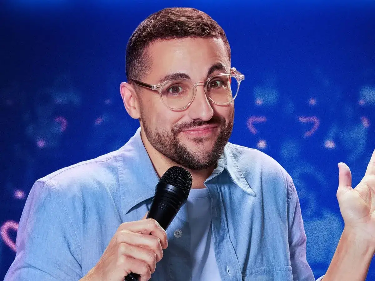 Un c&oacute;mico con gafas y camisa azul, micr&oacute;fono en mano, listo para su show en Galder Varas Madrid.