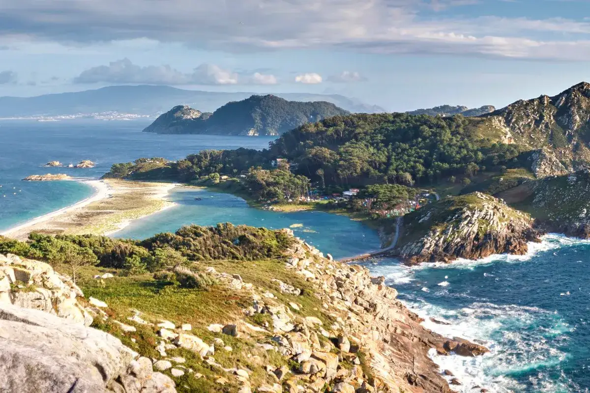 Paisaje costero con playas de arena blanca y aguas turquesas, rodeado de vegetaci&oacute;n y rocas. Un rinc&oacute;n id&iacute;lico de los pueblos R&iacute;as Baixas.