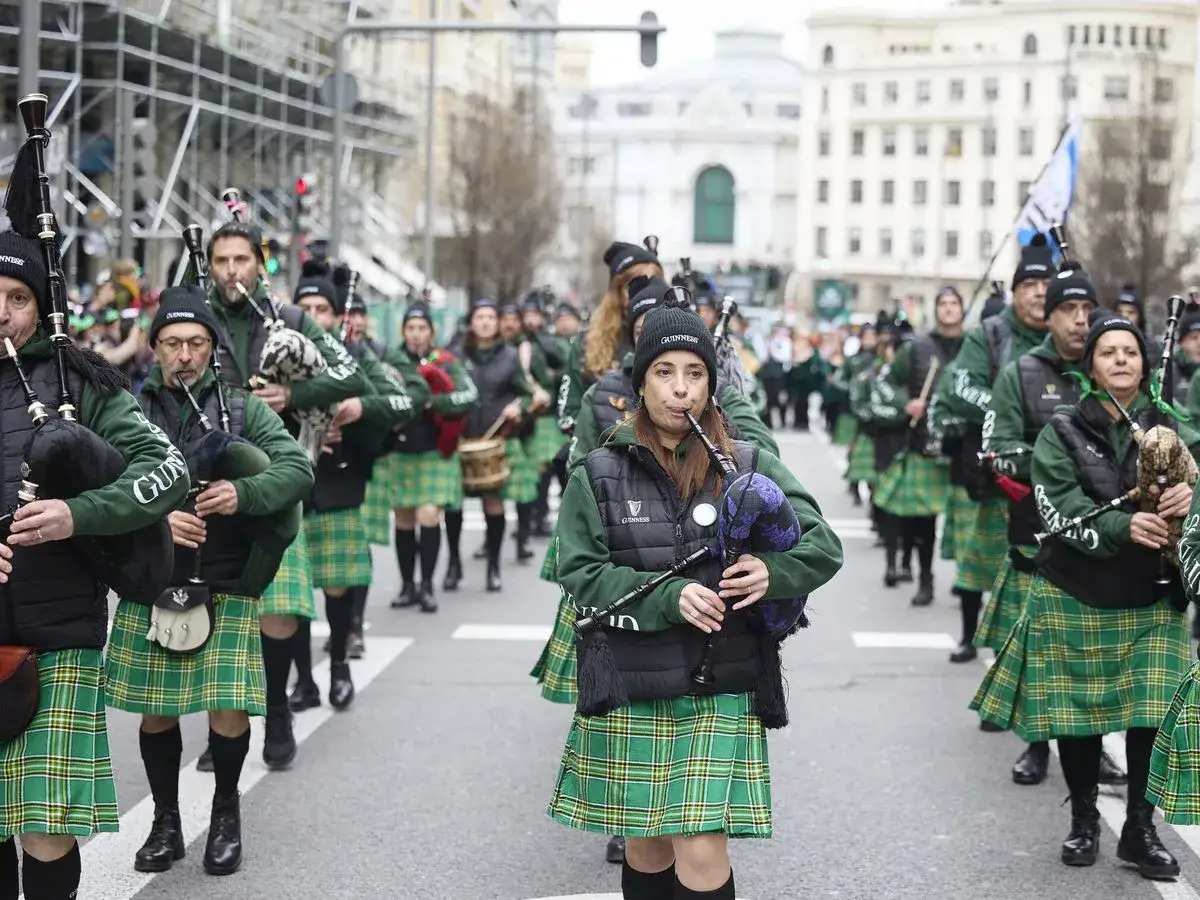 Gente con kilt verde y gaitas participa en un desfile san patricio.