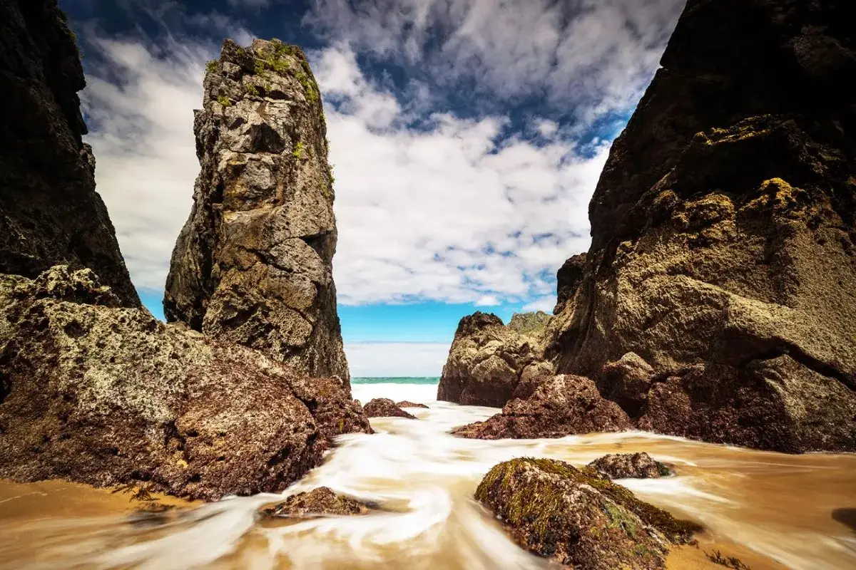 Impresionantes formaciones rocosas en una playa de España, con el mar y el cielo azul de fondo. Un rincón idílico entre las playas bonitas en España.