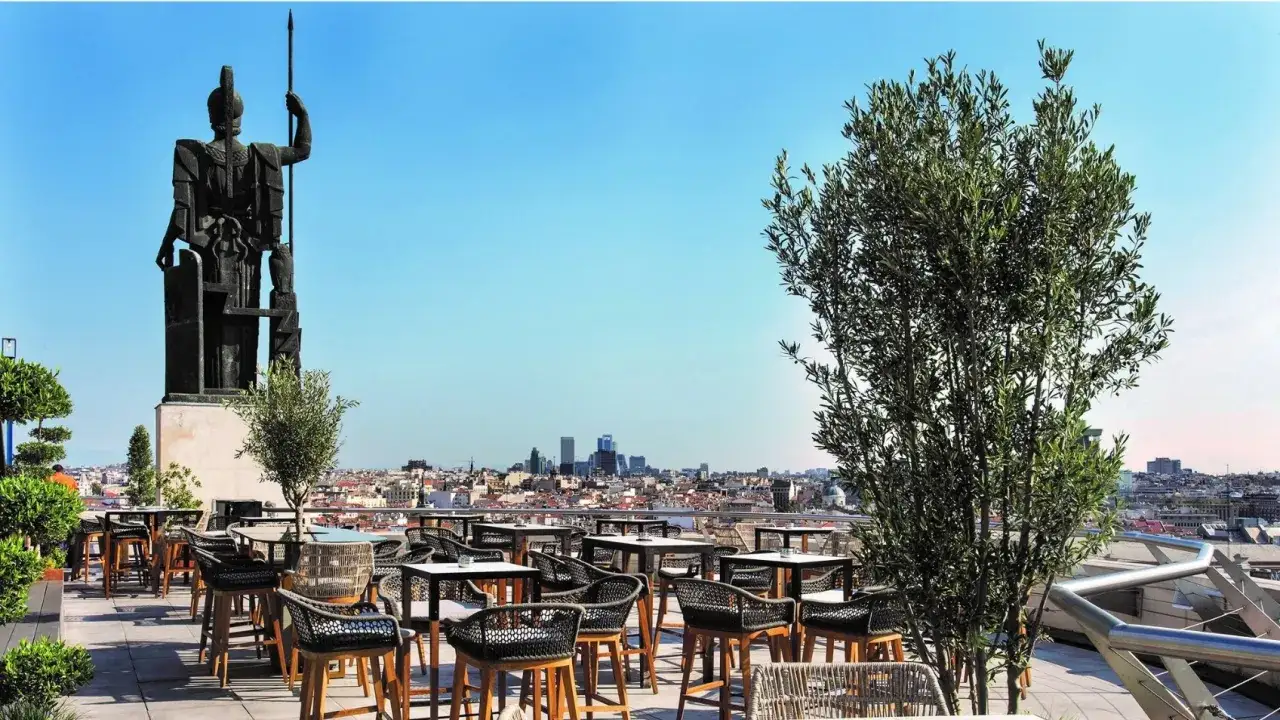 Terraza Bellas Artes Madrid con vistas a la ciudad. Una estatua monumental preside el espacio, rodeado de mesas y sillas de dise&ntilde;o.